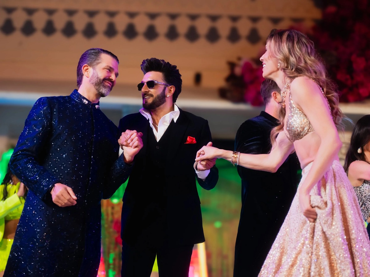People dancing and smiling at a festive event, wearing formal and glamorous attire.