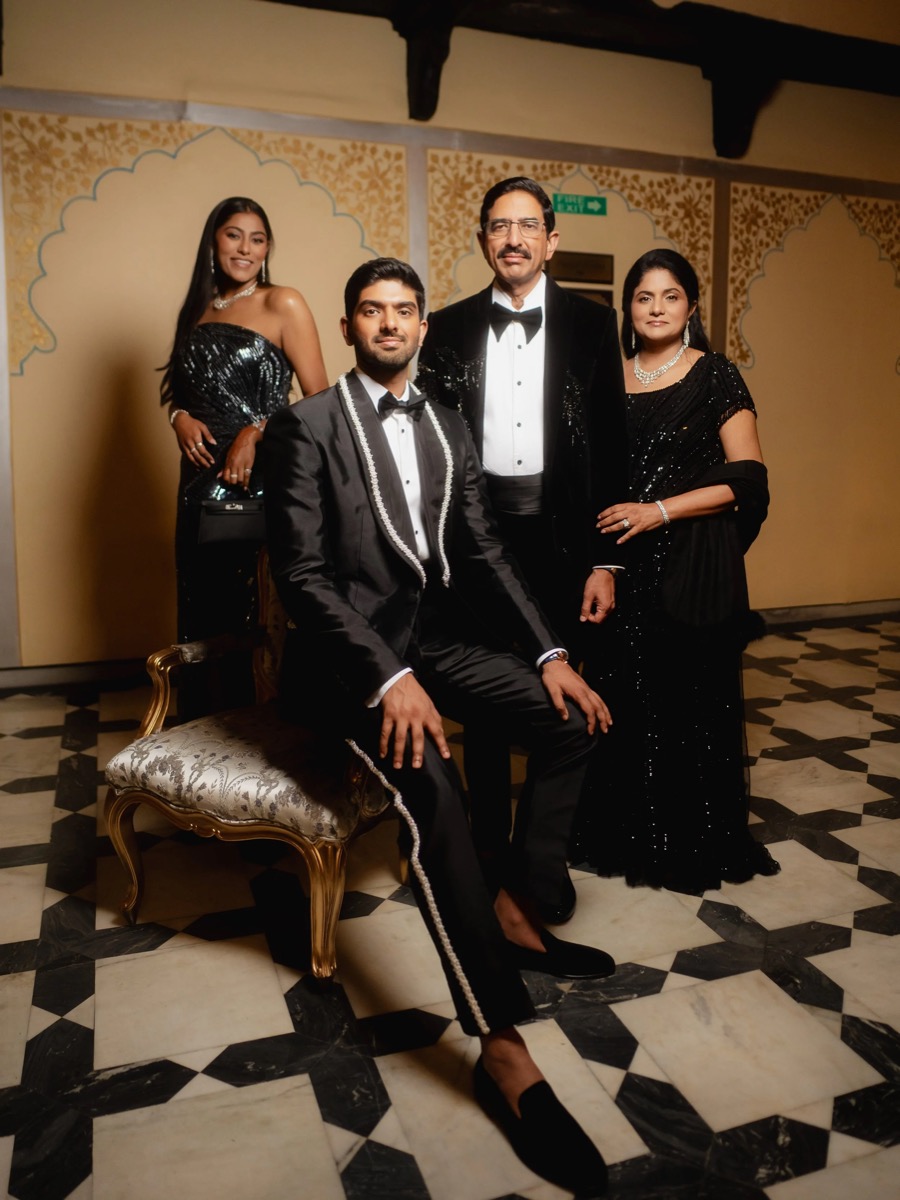 Four people dressed in formal black evening wear posing for a photo indoors with ornate decor.
