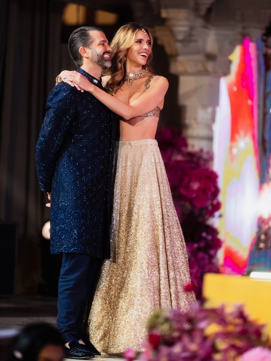 A man and woman dancing and smiling at an event with colorful lighting and flower decorations.